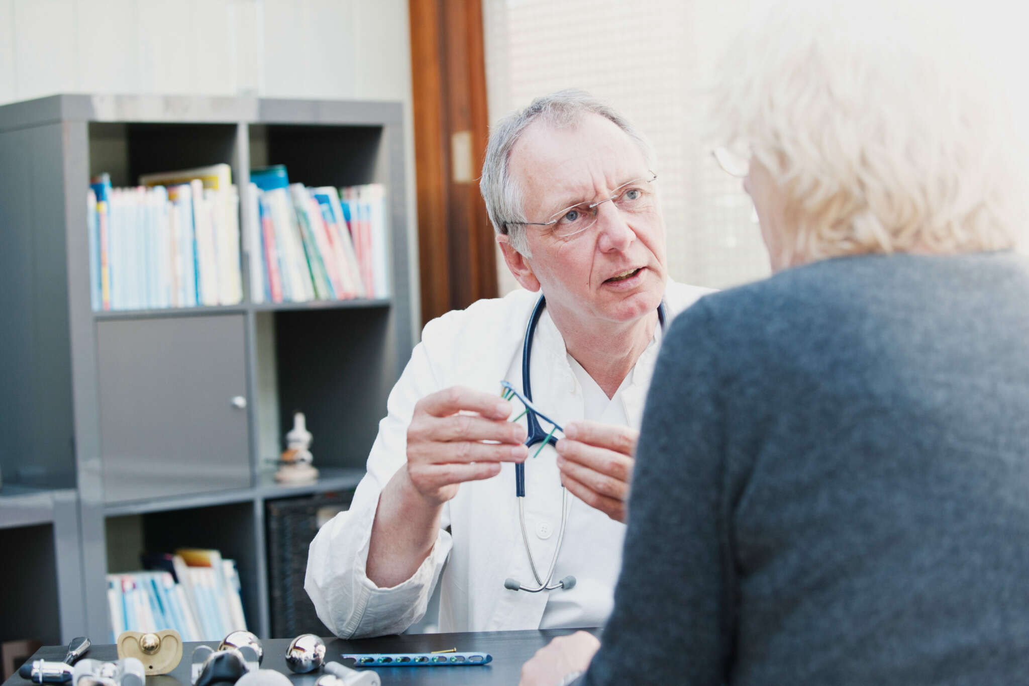 Arzt im mittleren Alter schaut seiner Patientin ins Gesicht, während er ihr etwas erklärt