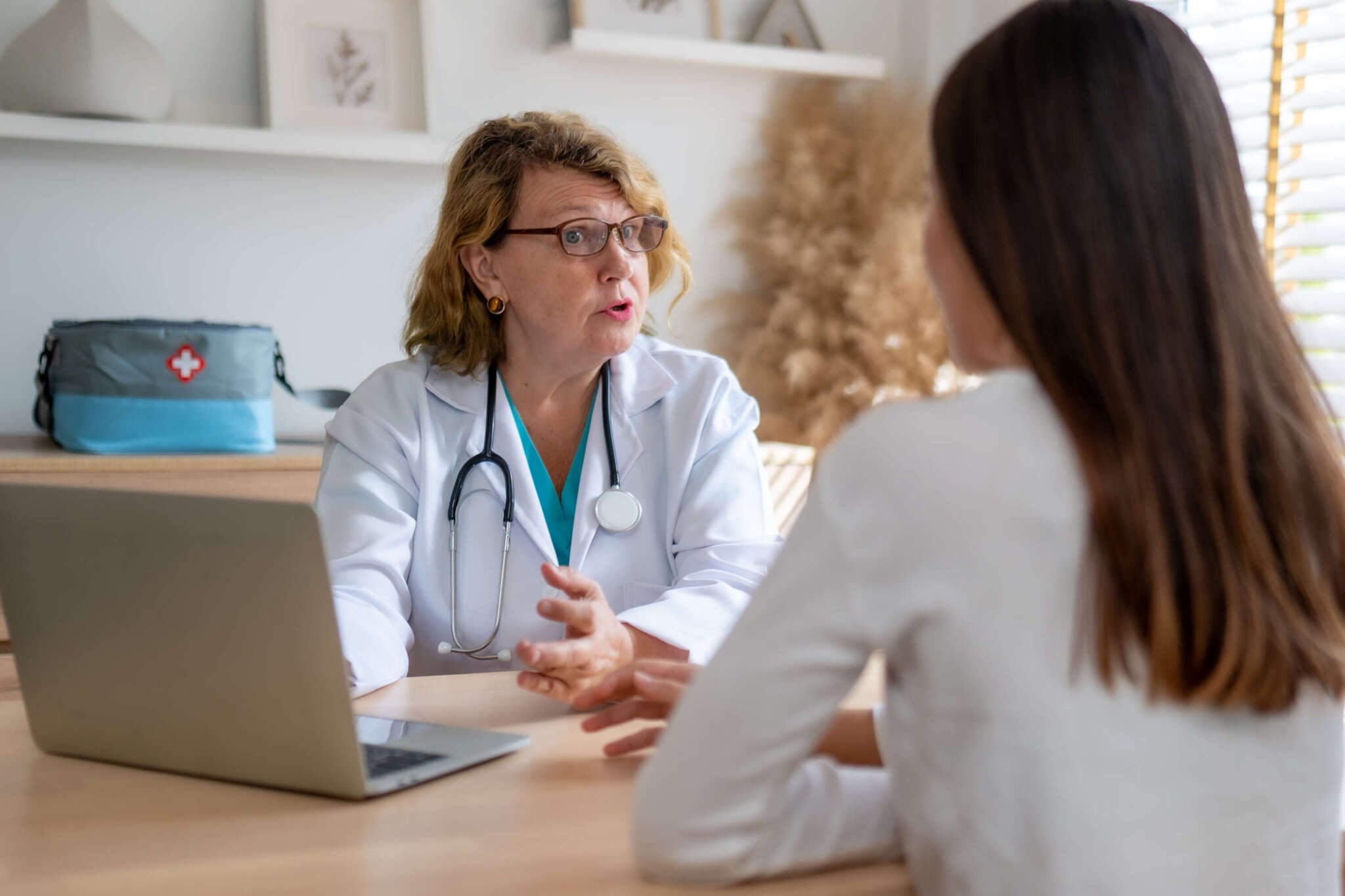 Ärztin berät Patientin im Sprechzimmer am Tisch