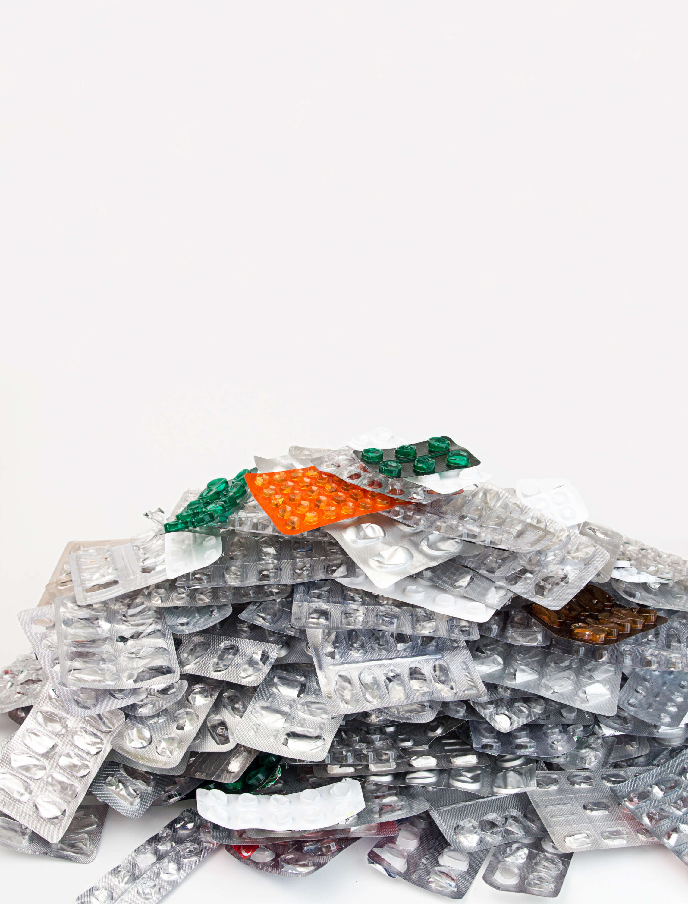 Ein Haufen leerer Blisterpackungen mit verschiedenfarbigen Tabletten auf weißem Hintergrund.