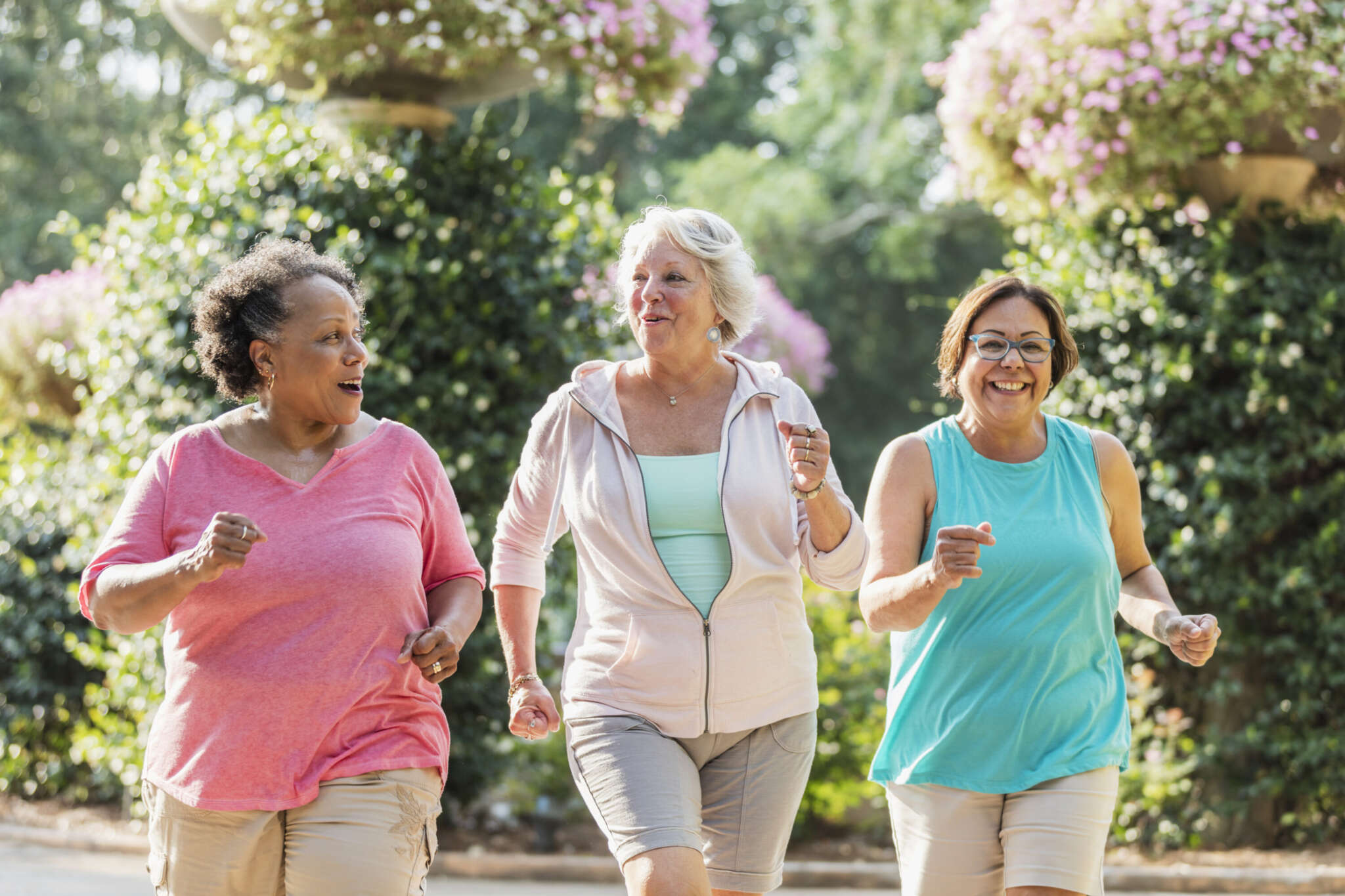 Drei Frauen joggen gemeinsam im Park und unterhalten sich.