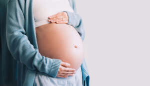 Schwangere Frau hält beide Hände auf den Babybauch.